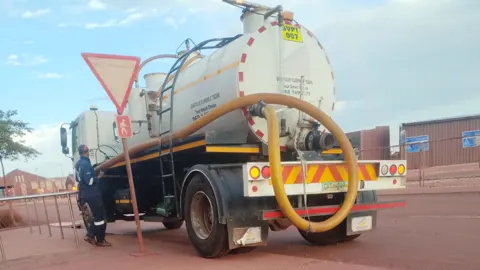 Smartvalve's white honey sucker truck, SVPT 007, with its yellow suction hose, at a site